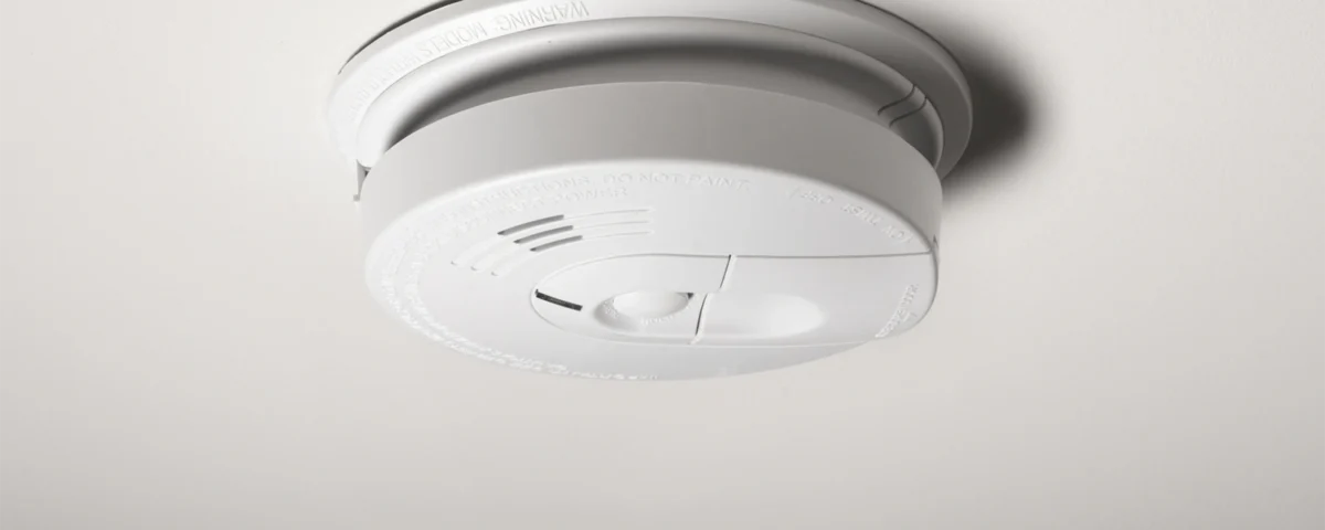 Smoke detector beeping randomly at night on a hallway ceiling, indicating a fire alarm low-battery or sensor issue