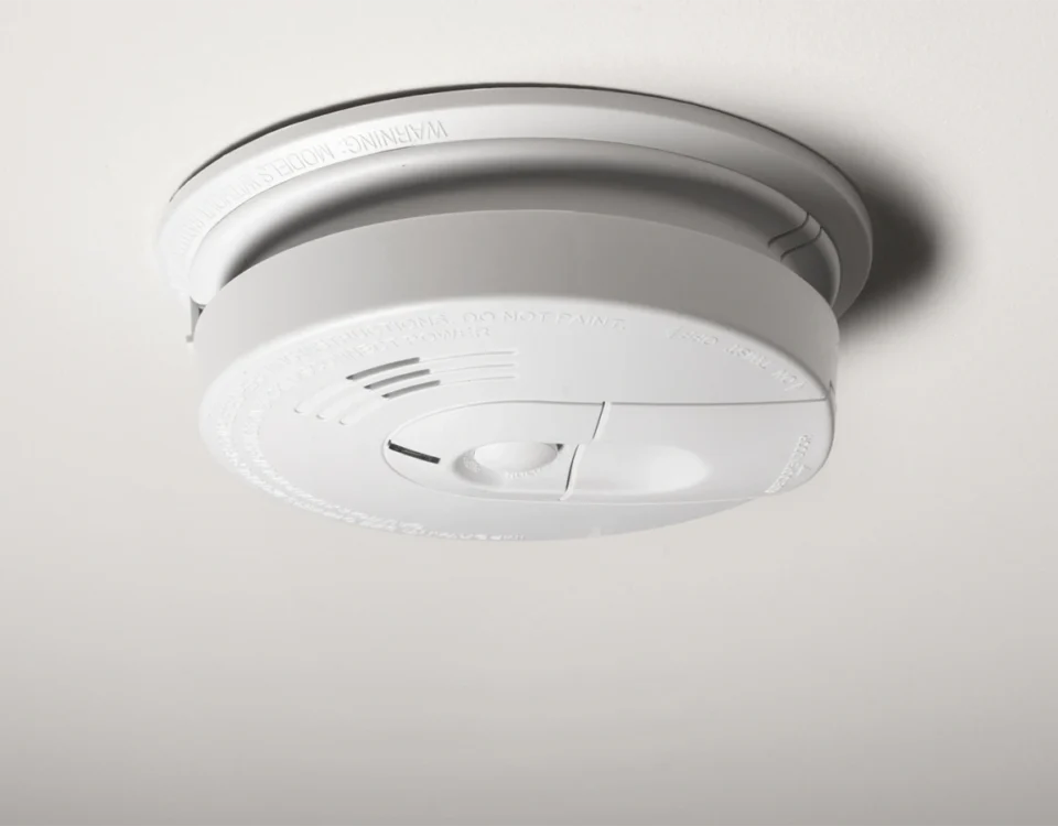 Smoke detector beeping randomly at night on a hallway ceiling, indicating a fire alarm low-battery or sensor issue