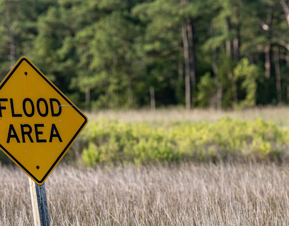 Yellow “Flood Area” warning sign near a Sacramento roadway, highlighting local flood zone risks